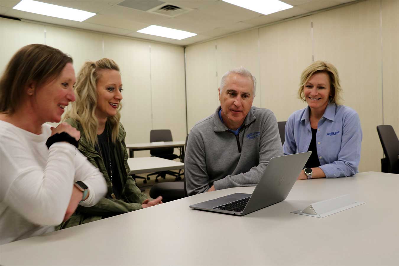 DSU College of Education and Human Performance faculty gathered around a computer.
